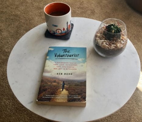 Image of book 'The Voluntourist' on a table with coffee and cactus.