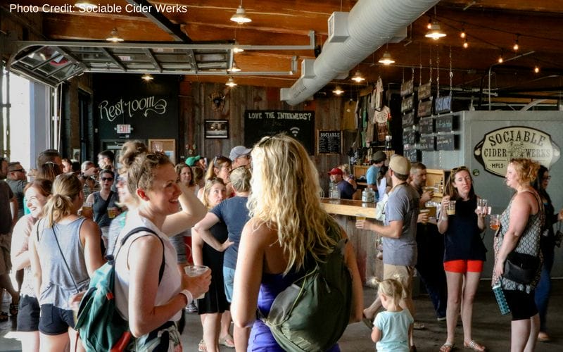 Sociable Cider Werks is one of the best Minneapolis breweries, located in the Northeast neighborhood near Central Ave. A crowded taproom with wood walls, ceiling and bar. A wall of garage style doors is open to the outside.