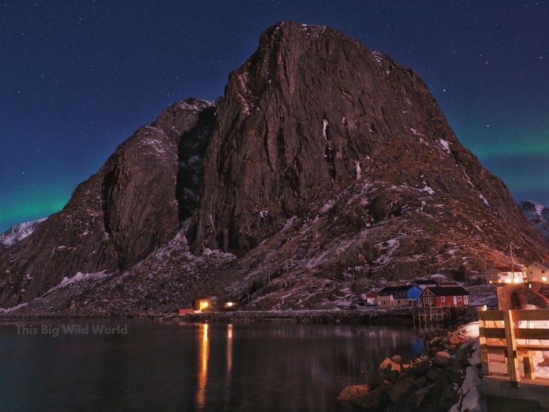 Photograph the Northern Lights with a mirrorless camera. Here they are peeking out from behind a mountain in the Lofoten Islands in Norway.