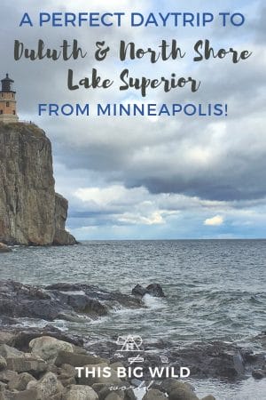 Text: A perfect daytrip to Duluth & North Shore Lake Superior from Minneapolis!
Image: On the left is tall and rugged granite rock with a pale peach lighthouse on it. The lighthouse looks out onto dark blue water below, with a rocky shoreline in the foreground. Above is a cloudy sky. This is Split Rock Lighthouse in Minnesota.