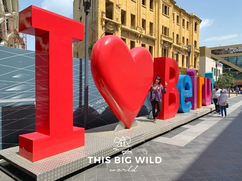 Me standing with a large brightly colored sign that says "I Love Beirut" located at the Beirut Souk.
