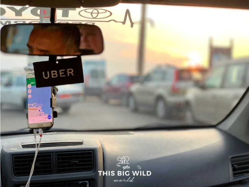 View of bright orange and yellow sunset sky through the front window of an Uber driving through Beirut.