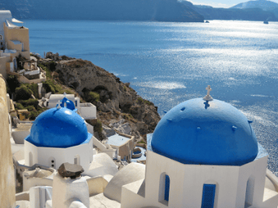 Blue domes and bright white buildings overlooking the Mediterranean Sea in Santorini Greece.