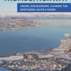 Text: Winter Adventure Guide Tromso Norway - Hiking, dog sledding, chasing the northern lights and more! Image: View of the island of Tromso from above with snow covered mountains all around it.