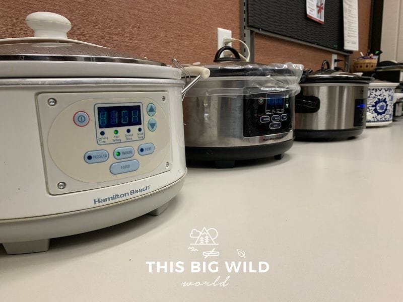 Crockpots of all types lined up on a table for a potluck dinner in Minnesota.