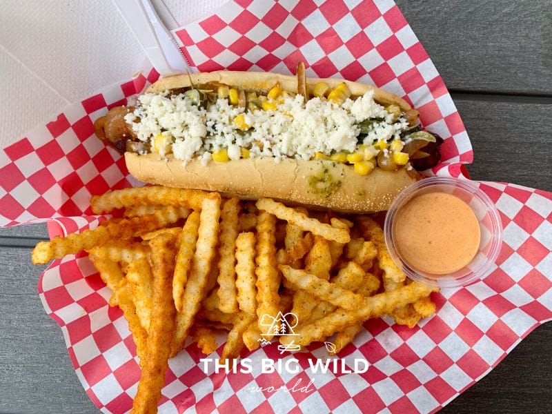 The Phoenix hot dog is wrapped in bacon and topped with corn, poblanos, and crema with a side of smokey chili fries from International House of Hotdogs in Anchorage.