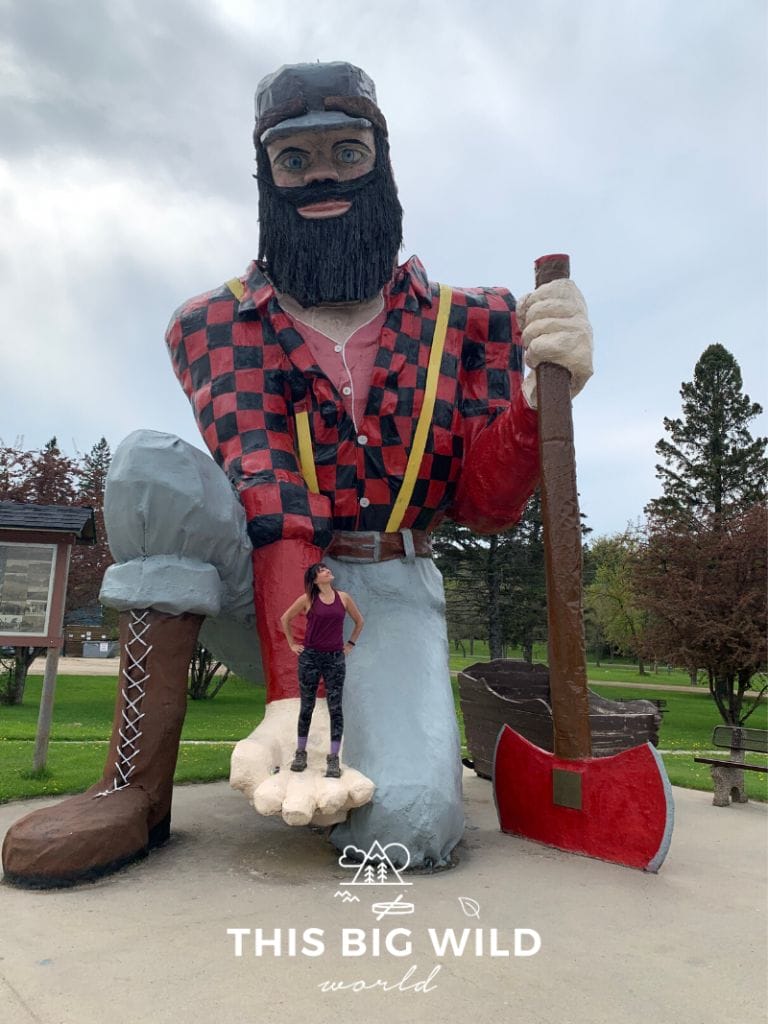 Standing in the hand of a statue of Paul Bunyan in Akeley Minnesota. The statue is more than 25 feet tall and is one of many Paul Bunyan statues throughout Minnesota.