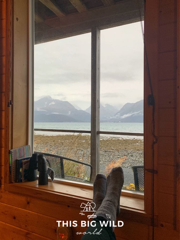 Window overlooking Resurrection Bay with snowcapped mountains in the distance. My feet are resting on the windowsill next to binoculars.