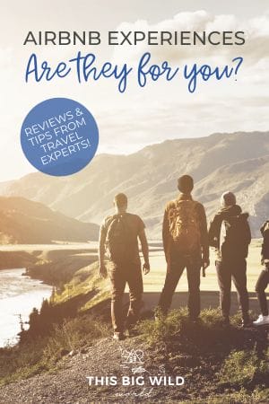 Text: Airbnb Experiences - Are they for you? Reviews & tips from travel experts!
Image: Group of people with their backs to the camera looking at mountains in the distance from a hiking trail. The sun is low in sky off to the left of the frame.