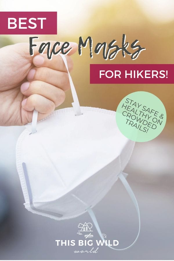 Text: Best Face Masks for Hikers! Stay safe & healthy on crowded trails.
Image: A hand is on the left side of the frame, holding a white face mask by the ear loop. the background is blurred but green and a hint of sunshine from the top right corner.