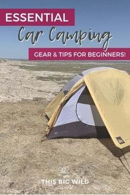 Text: Essential Car Camping Gear & Tips for Beginners!
Image: Yellow, white and black tent on brown dry grass overlooking the Badlands below with a blue sky overhead.
