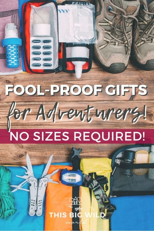 Text: Fool-proof gifts for Adventurers! No sizes required! Image: A flat lay of outdoor and travel items laid out on a wooden surface, including hiking shoes, a headlamp and a multi-tool.