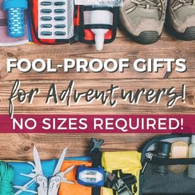Text: Fool-proof gifts for Adventurers! No sizes required! Image: A flat lay of outdoor and travel items laid out on a wooden surface, including hiking shoes, a headlamp and a multi-tool.