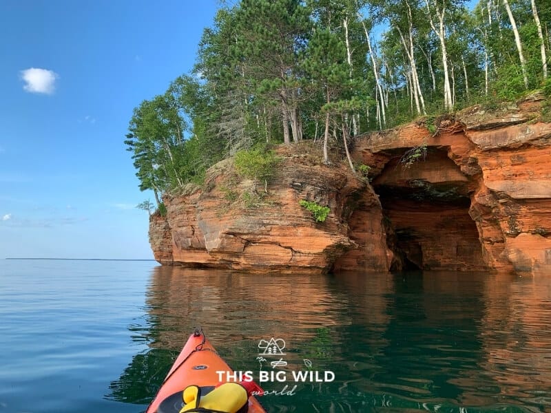 Bright red rocks of the Apostle Islands National Lakeshore near Bayfield Wisconsin as seen from inside of a kayak on Lake Superior.