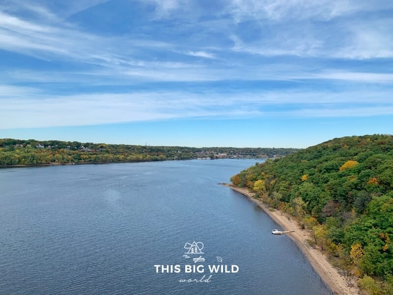 The St Croix River in summertime with bright green forest on either side. On the left is Stillwater in Minnesota and on the right is Wisconsin. 