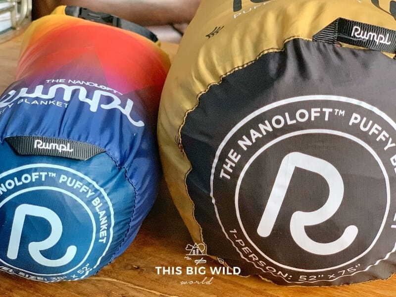 The ends of two Rumpl Nanoloft blanket stuff sacks laying side by side on a wooden surface.