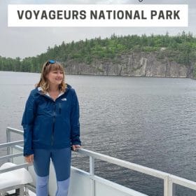 Text: Houseboat Packing List Voyageurs National Park Image: Me Standing on the roof of a houseboat wearing a rain jacket and leggings with sandals.