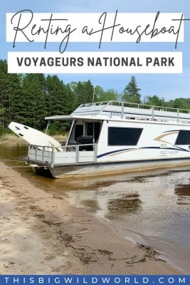 Text: Renting a houseboat Voyageurs National Park  Image: Houseboat on a beach with trees behind it.