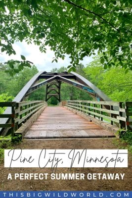 Text: Pine City, Minnesota - A Perfect Summer Getaway
Image: A metal and wood bridge appears hidden in a forest on a cloudy day.