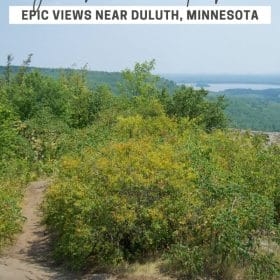 Text: Ely's Peak Loop Trail, epic views near Duluth, Minnesota Image: 360 degree view of lush green vegetation with water off in the distance near the horizon.