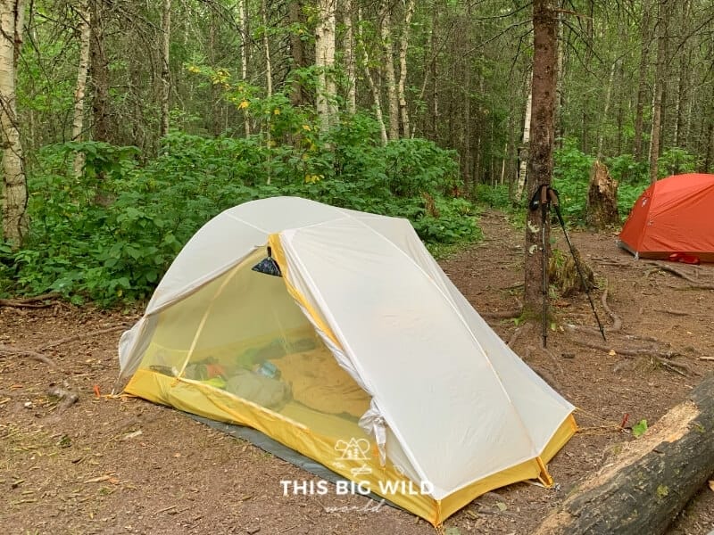 A yellow Big Agnes Tiger Wall tent has a gray rain fly over it at the North Little Brule River campsite on the Superior Hiking Trail.