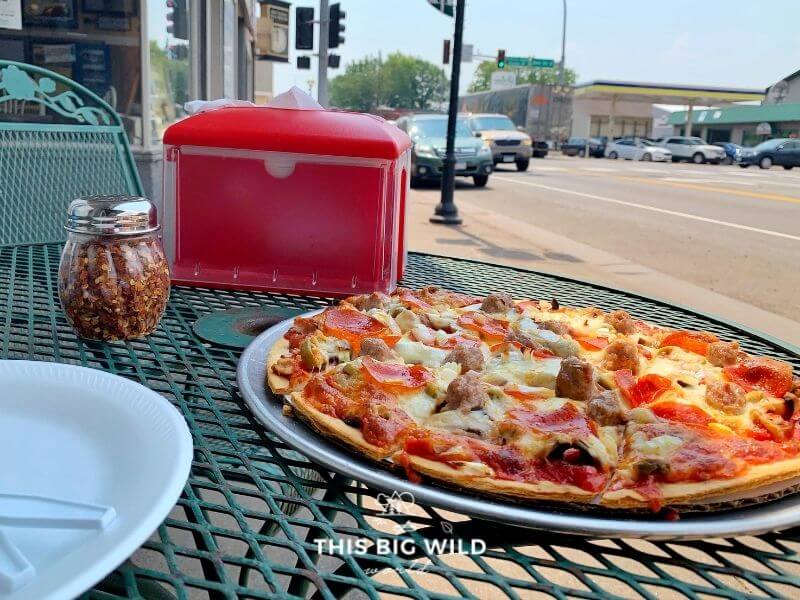 Close up of a pizza from Proctor Pizza & Sub Shop at an outdoor dining table.