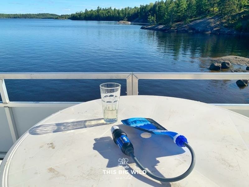 Sawyer Squeeze water filter next to a glass of clear water on the rooftop of a houseboat in Voyageurs National Park.