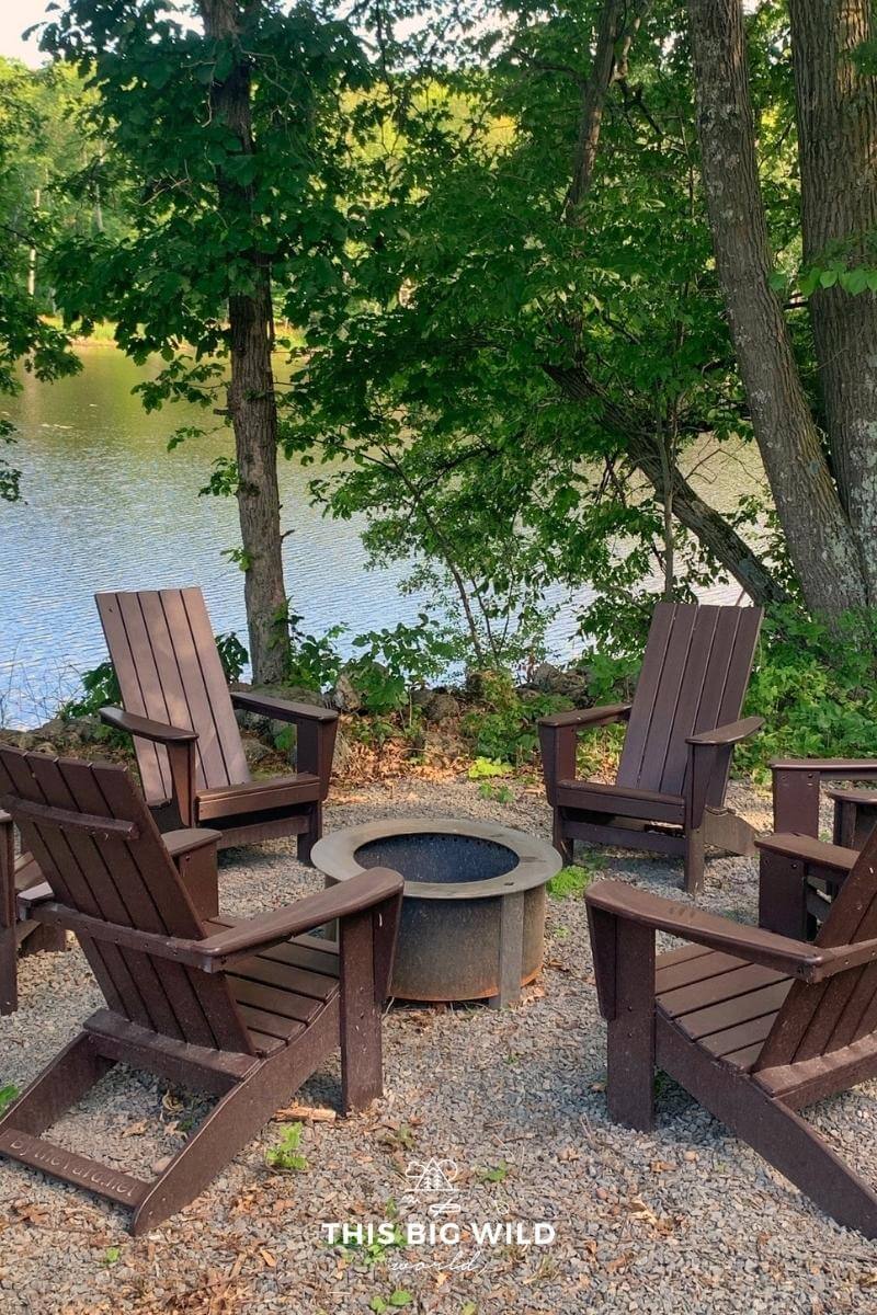 Adirondack chairs are seated around a firepit near the small lake on Nordlys property in Wisconsin.