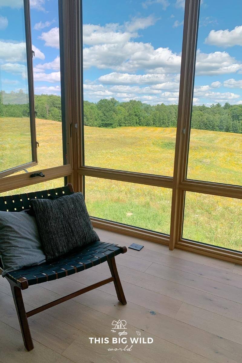 A Scandinavian inspired chair in the bedroom at Nordlys Airbnb with a view of wildflowers out the window.
