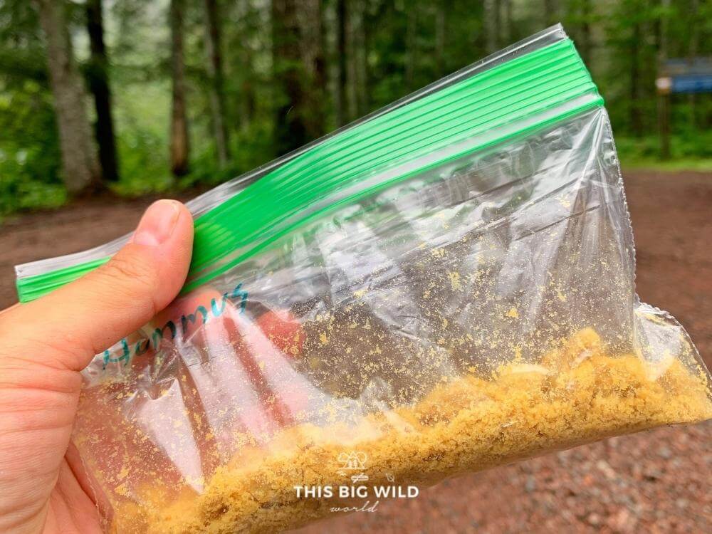 Small ziploc bag with powdered hummus in it with a forest in the background.