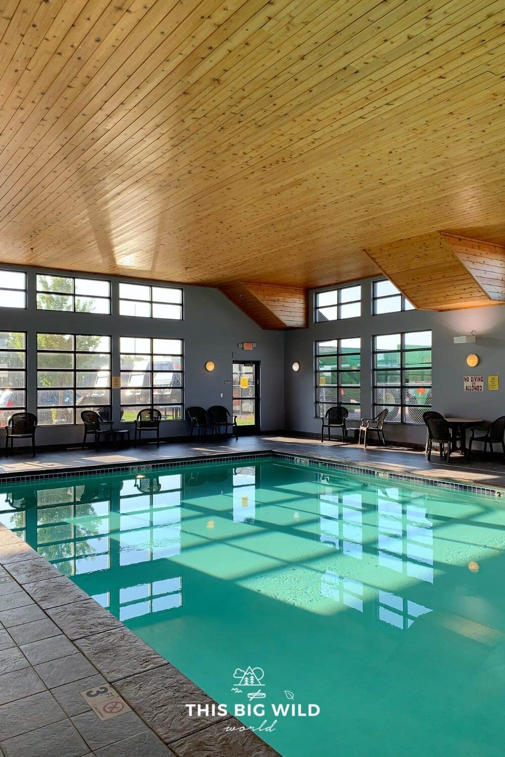Indoor heated pool with lots of natural light and a wood ceiling.