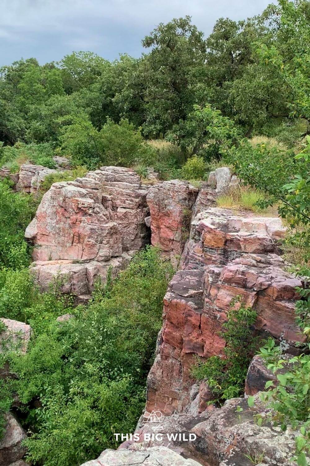 Pinkish red pipestone cliffs surrounded by greenery.