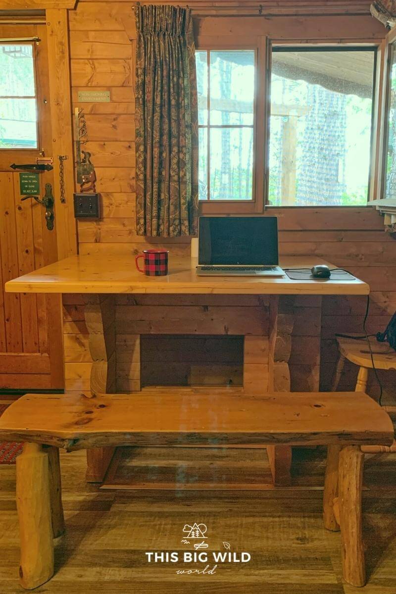 A rustic wooden table with bench sits right in front of a window at The Timberjack cabin. A perfect place for remote work or creative writing.