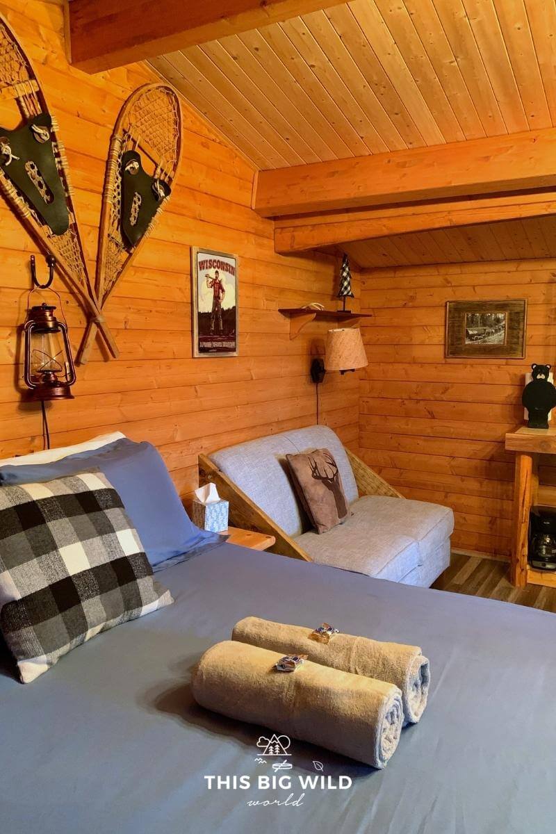 Hayward Cabins are open space with a queen size bed next to a small pullout sofa with lumberjack-inspired decor.