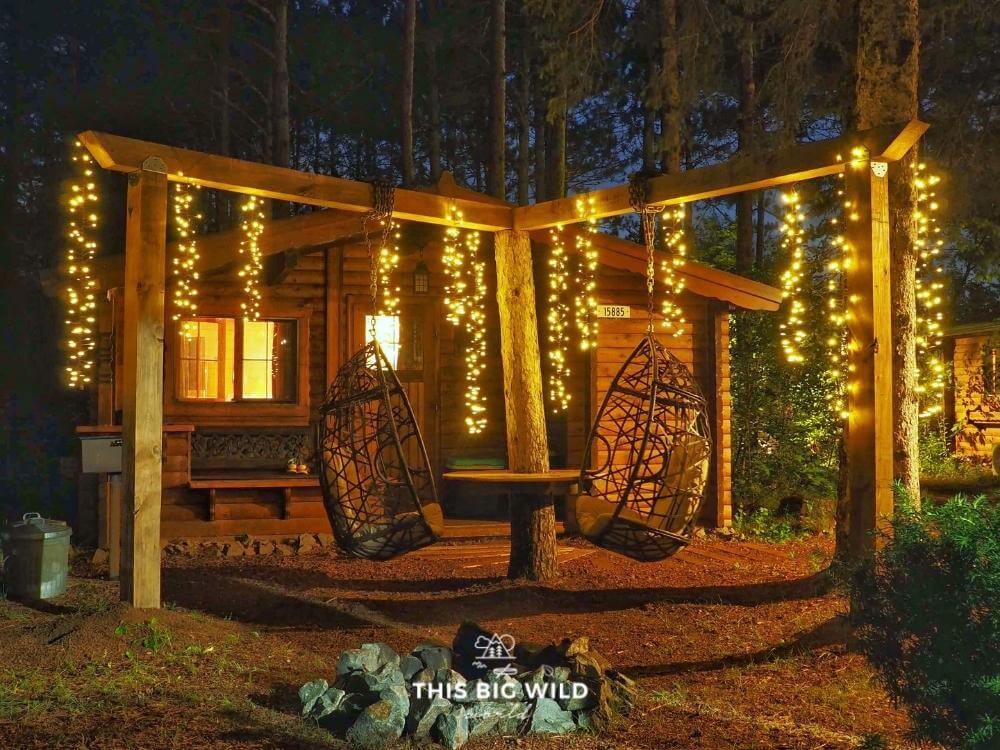 The outdoor space at The Timberjack at Hayward Cabins has hanging chairs and twinkle lights.