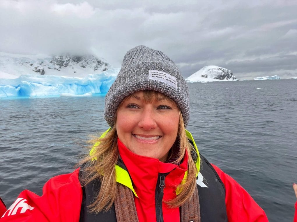 Me in a zodiac boat in Antarctica with icebergs behind me