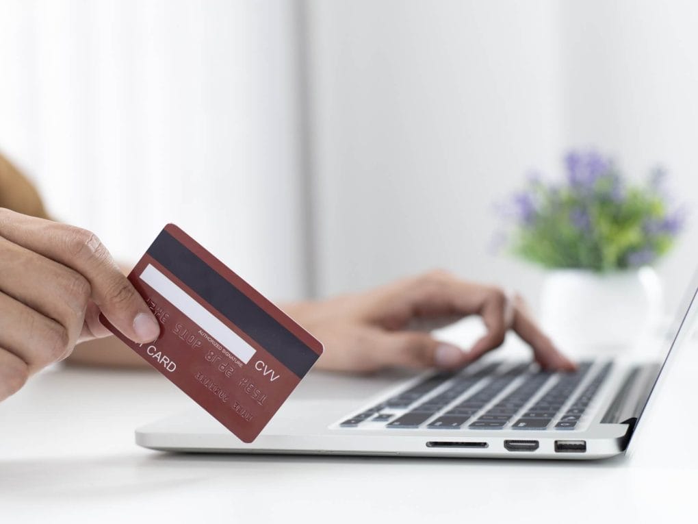One hand holding a credit card and the other resting on a keyboard.
