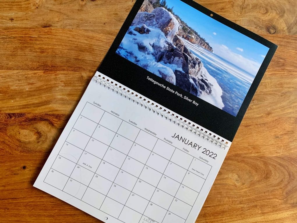 A calendar lays flat on a wooden table with a photo of Lake Superior's north shore.